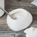 A white Libbey porcelain sugar pot with a spoon in it.