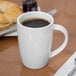 A close up of a Libbey white porcelain mug with brown liquid in it.