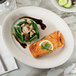 A Tuxton Hampshire oval china platter with salmon, green beans, and a slice of lemon on it.