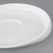 A close-up of a Libbey Slenda Verve white porcelain saucer with a curved edge.