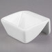 A white square bowl with a curved corner and a handle.