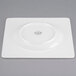 A white square porcelain plate with a circular design.