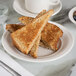 A Tuxton Hampshire eggshell embossed china plate topped with toast on a table.
