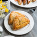 A Libbey Royal Rideau white porcelain plate with scones and pastries on a table with a cup of coffee.