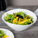 A white Libbey porcelain bowl filled with vegetable salad.
