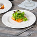 A Libbey white porcelain plate with lettuce on it and a fork.