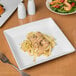 A Libbey white porcelain coupe plate with pasta and salad on it.