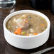 A bowl of Reserve by Libbey Royal Rideau white porcelain bouillon with soup and vegetables.