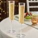 A pair of clear plastic champagne flutes filled with sparkling beverage on a table.