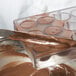 A person using a Chocolate World 24 compartment cup chocolate mold to spread chocolate on a tray.