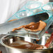 A person pouring chocolate into a Matfer Bourgeat large half sphere chocolate mold.