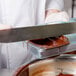 A person using a knife to cut chocolate in a Matfer Bourgeat egg chocolate mold.