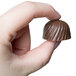 A hand holding a chocolate rose made with a Chocolate World roses candy mold.