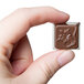 A hand holding a chocolate with a flower design.