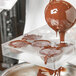 A person pouring chocolate into a Chocolate World large half spheres candy mold.