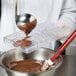 A person pouring chocolate into a plastic tray.