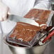 A person spreading chocolate in a Matfer Bourgeat chess piece mold.