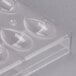 A clear plastic Chocolate World quenelle mold with teardrop-shaped compartments.