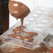 A person pouring chocolate into a Chocolate World quenelle mold.