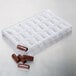A white plastic polycarbonate tray with 24 bullion-shaped chocolates.