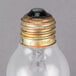 A close up of a Satco clear rough service light bulb with a gold cap.