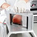 A person using white gloves to cut a piece of fruit with a Vollrath Redco InstaSlice Fruit and Vegetable Cutter.