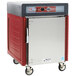 A red and silver Metro insulated hot holding cabinet with wheels.