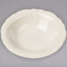 A white Homer Laughlin Carolyn fruit bowl with a scalloped edge on a gray surface.