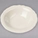 A white Homer Laughlin bowl with a small scalloped edge on a gray surface.