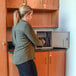 A woman opening a metal box with several rectangular slots inside.