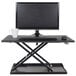 A black Luxor stand up desktop desk with a computer monitor and keyboard on it.