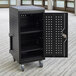 A black metal cart with a door open containing a Luxor LLTM24-B tablet charging station.