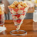 A Clipper Mill spiral metal cone basket filled with fries on a table.