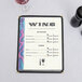 An 8 1/2" x 11" menu with a wave border on a table with wine glasses and a glass of wine.