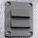 A grey rectangular metal wall plate with two holes.