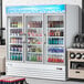 An Avantco white swing glass door merchandiser refrigerator with drinks and beverages on shelves.