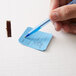 A hand using a blue pen to fill out a paper with 50/50 Marquee Raffle tickets.