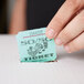 A close-up of a hand holding a green 50/50 raffle ticket.