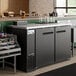 A black counter with Avantco Back Bar Refrigerators and bottles.