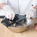A person using a Mercer Culinary hand slicer to cut slices of potatoes.
