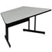 A grey trapezoid table top with black legs.