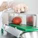 A person's hand using a Garde 3/16" tomato slicer on a tomato.