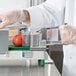 A person in white gloves using a Garde 3/16" Tomato Slicer pusher to cut a tomato.