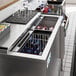 An Avantco stainless steel horizontal bottle cooler on a counter with bottles and glasses inside.