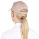 A woman with a ponytail wearing a beige Choice khaki 6-panel cap.