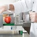 A person in white gloves using a Garde tomato slicer to cut a tomato.