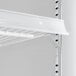 A white shelf with metal brackets inside a black glass door refrigerator.