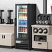 An Avantco swing glass door merchandiser refrigerator full of beverages.