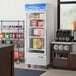 An Avantco white swing glass door merchandiser freezer with boxes of food.