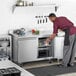 A man in a chef's uniform putting eggs in an Avantco worktop refrigerator.